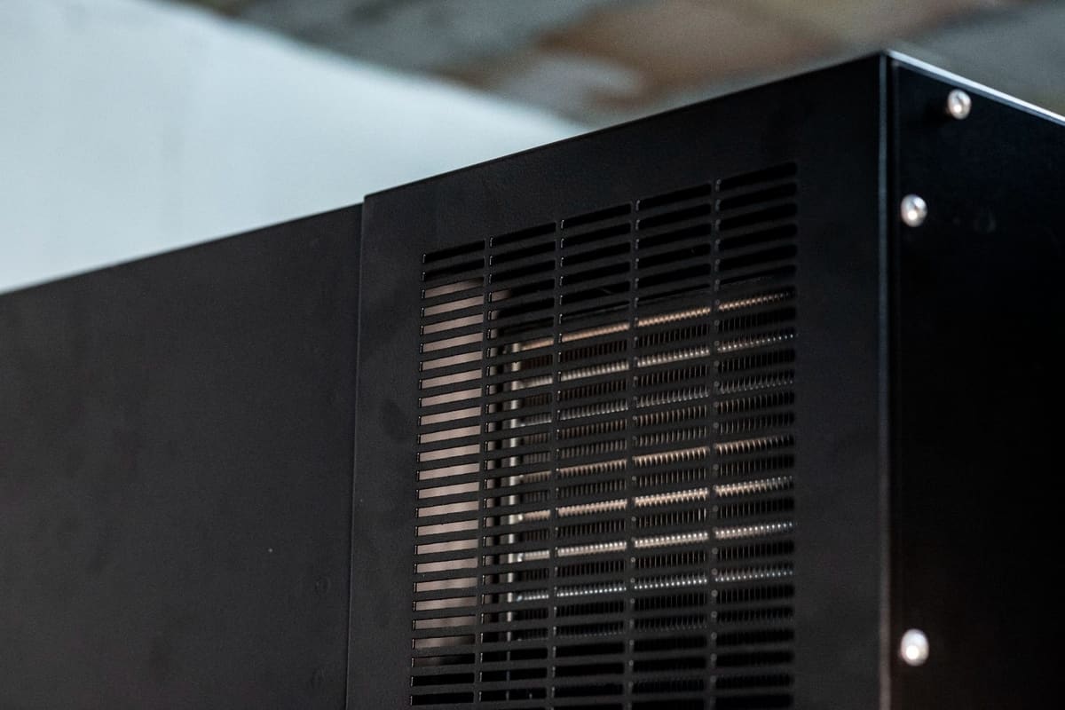 Griglia di ventilazione sulla lamiera nera di un armadio T-RACKS, con le alette dello scambiatore visibili dietro