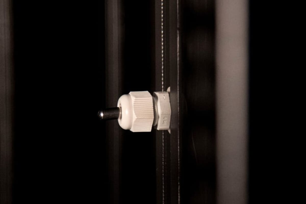 Pressacavo bianco che attraversa la parete di un armadio T-RACKS, con il cavo passante